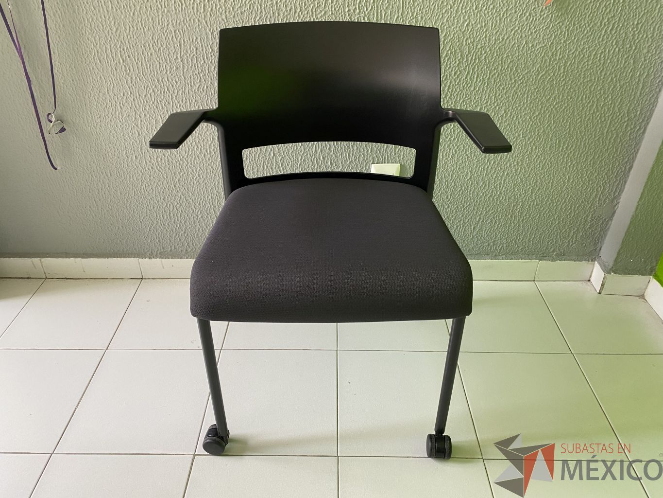 Lote 059 - Silla de visita con ruedas, asiento en tela, respaldo en plastico y descansabrazos fijos