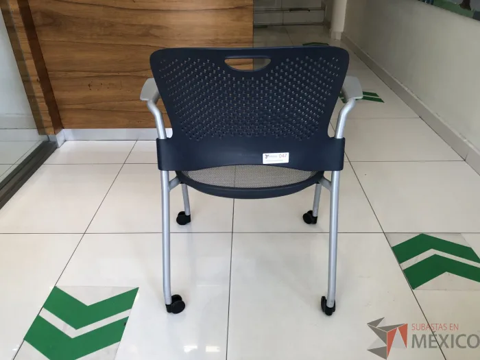 Lote 091 - Silla de visita con ruedas, descansabrazos, asiento en malla y respaldo en plástico color azul - Imagen 4