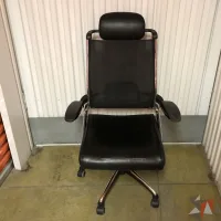 Lote 018 - Silla operativa con ruedas, descansabrazos, cabecera, asiento en piel y respaldo en malla color negro